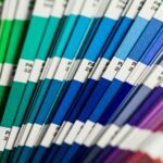 Ein aufgefalteter pantone Farbfächer von grün, über blau bis rot.
